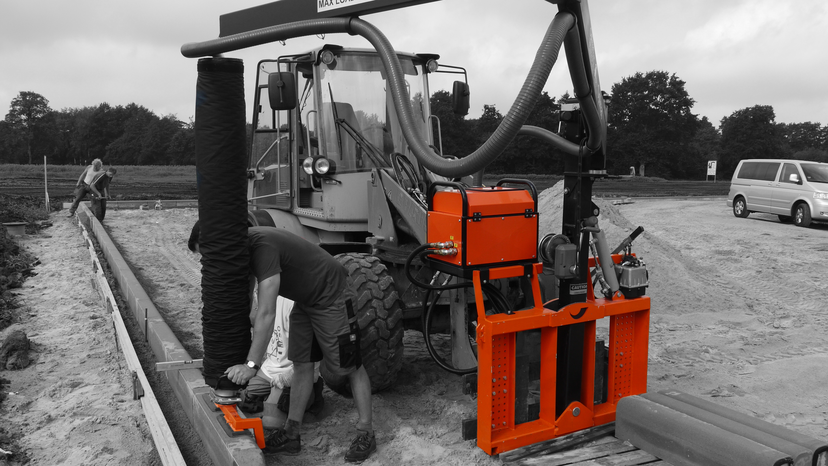 A construction site with a tractor and workers using machinery to lay down materials – Optimas.
