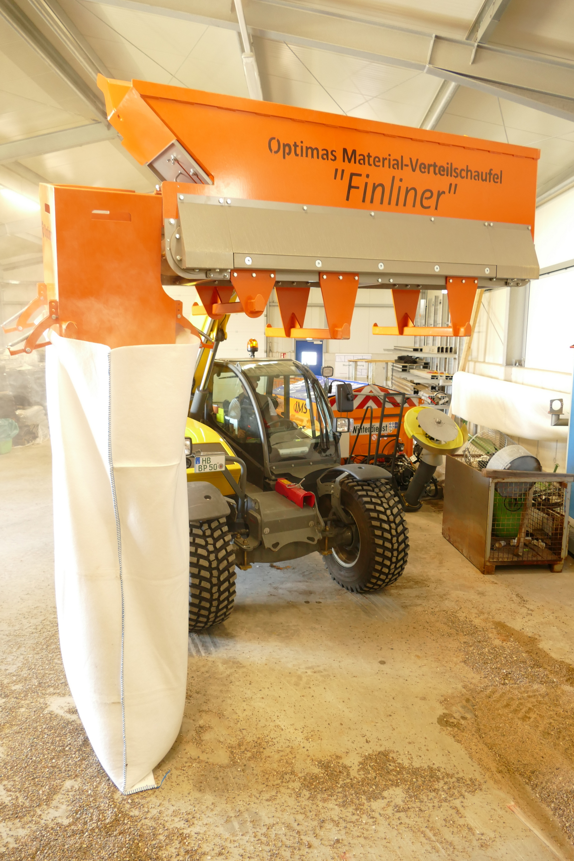 Optimas Finliner-Materialverteilerschaufel, montiert auf einem Traktor, zum präzisen Ablegen von Kies oder anderen Materialien – Optimas.