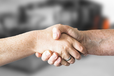 Gros plan de deux personnes se serrant la main, symbolisant un accord, un partenariat ou une négociation réussie avec un arrière-plan flou. – Optimas