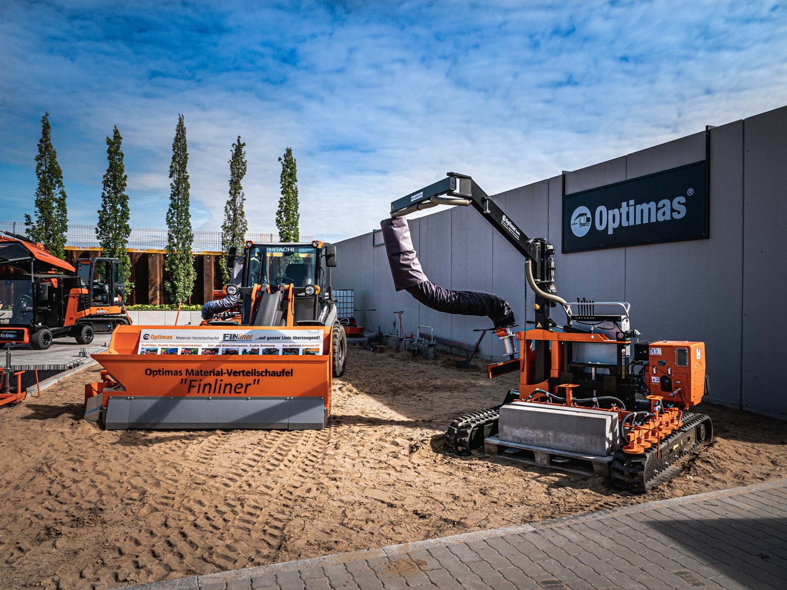 Construction equipment displayed outdoors, featuring a Finliner material distribution shovel and other machinery – Optimas.