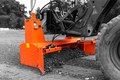 Close-up of an orange grading blade attached to construction machinery, efficiently leveling a gravel surface for road preparation – Optimas.