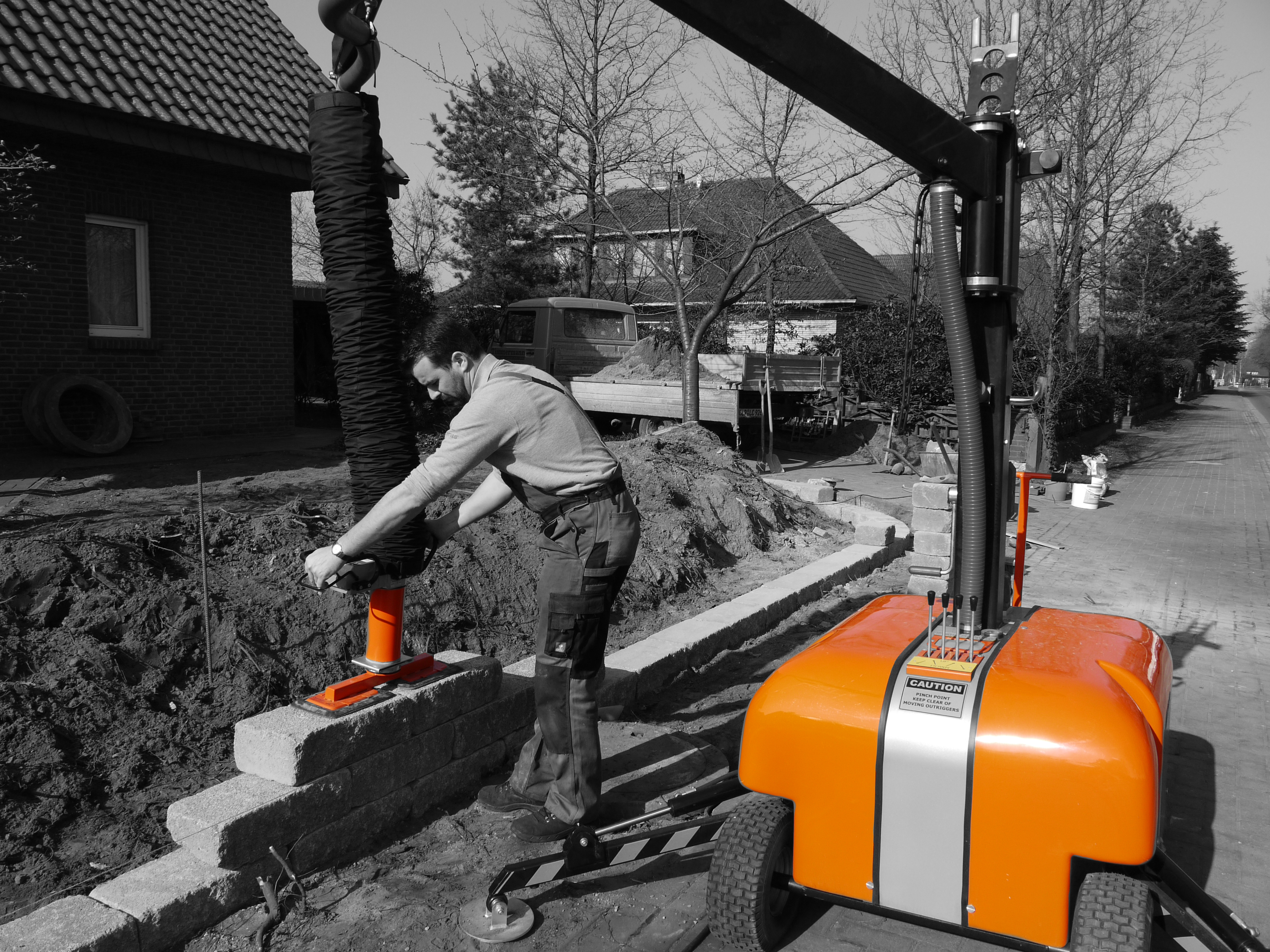 A worker operates a construction machine to lift a heavy object on a construction site – Optimas.
