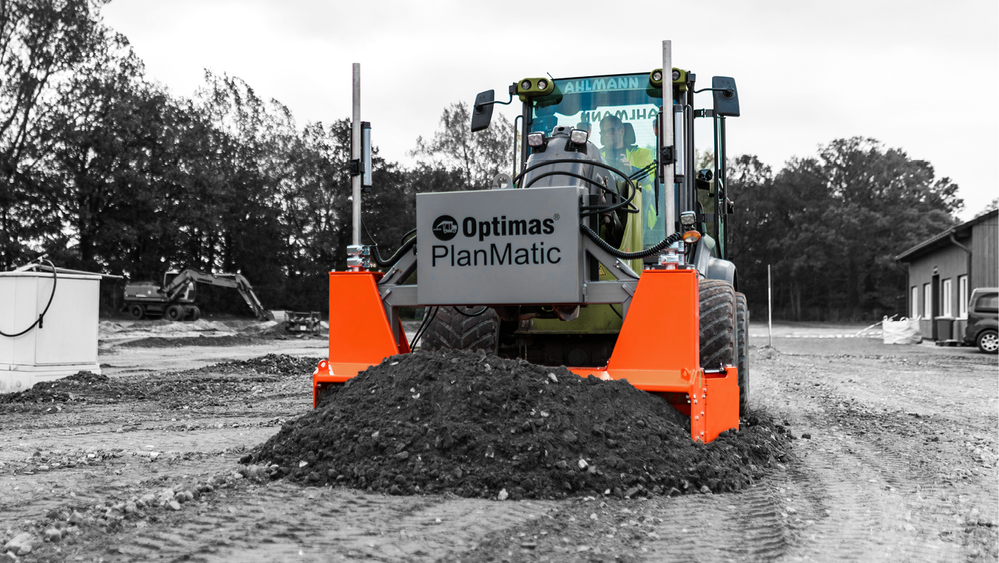 A close-up of an Optimus PlanMatic machine leveling a pile of dirt at a construction site, with black and white background – Optimas.