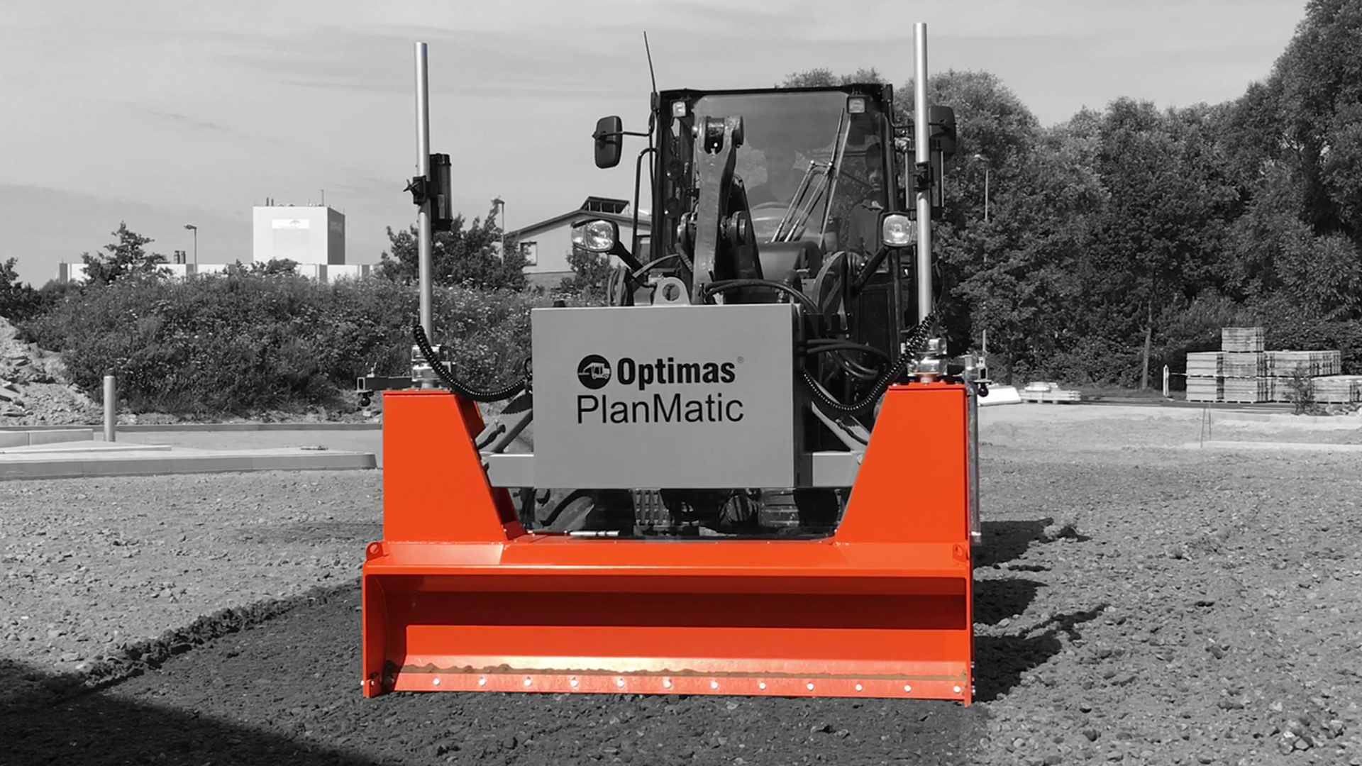 A front view of an orange snow plow attachment on a construction vehicle with a blurred background – Optimas.