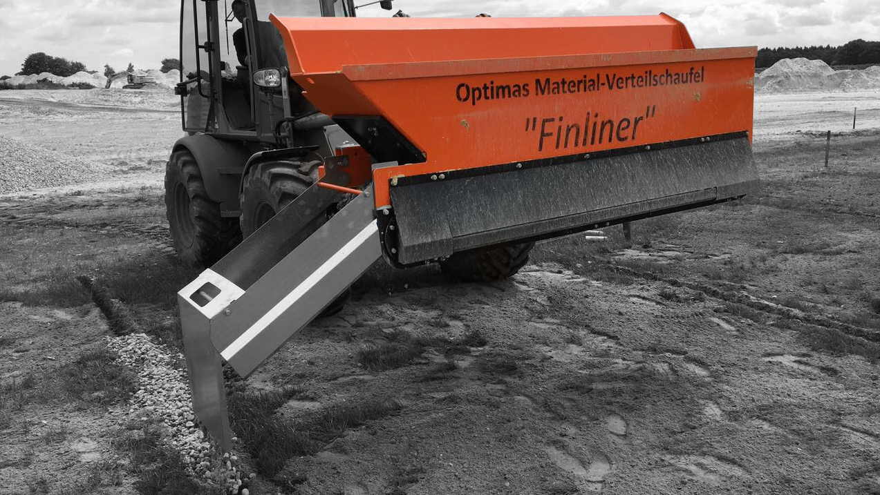 An orange material distribution shovel named 'Finliner' is leveling gravel on a construction site – Optimas.