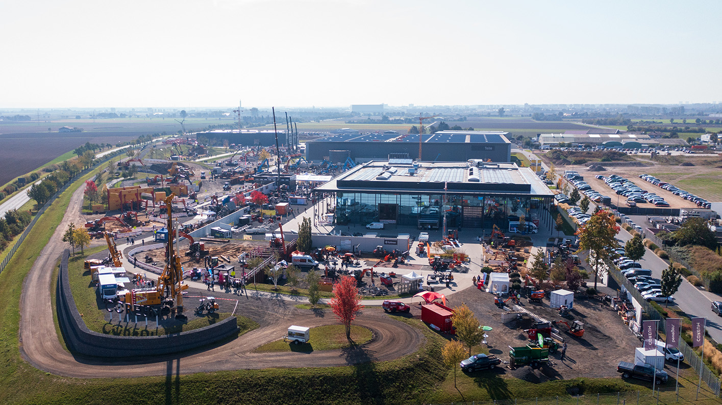 Aerial view of a large construction site with buildings, vehicles, and equipment surrounded by fields – Optimas