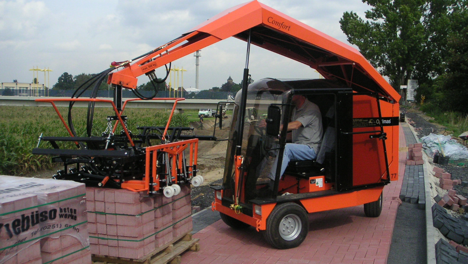 A worker operates a specialized brick-laying machine on a construction site, showcasing its functionality and design – Optimas.
