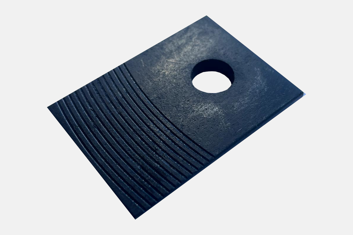 A black rubber pad with a textured surface and a central hole, designed for grip and stability – Optimas.