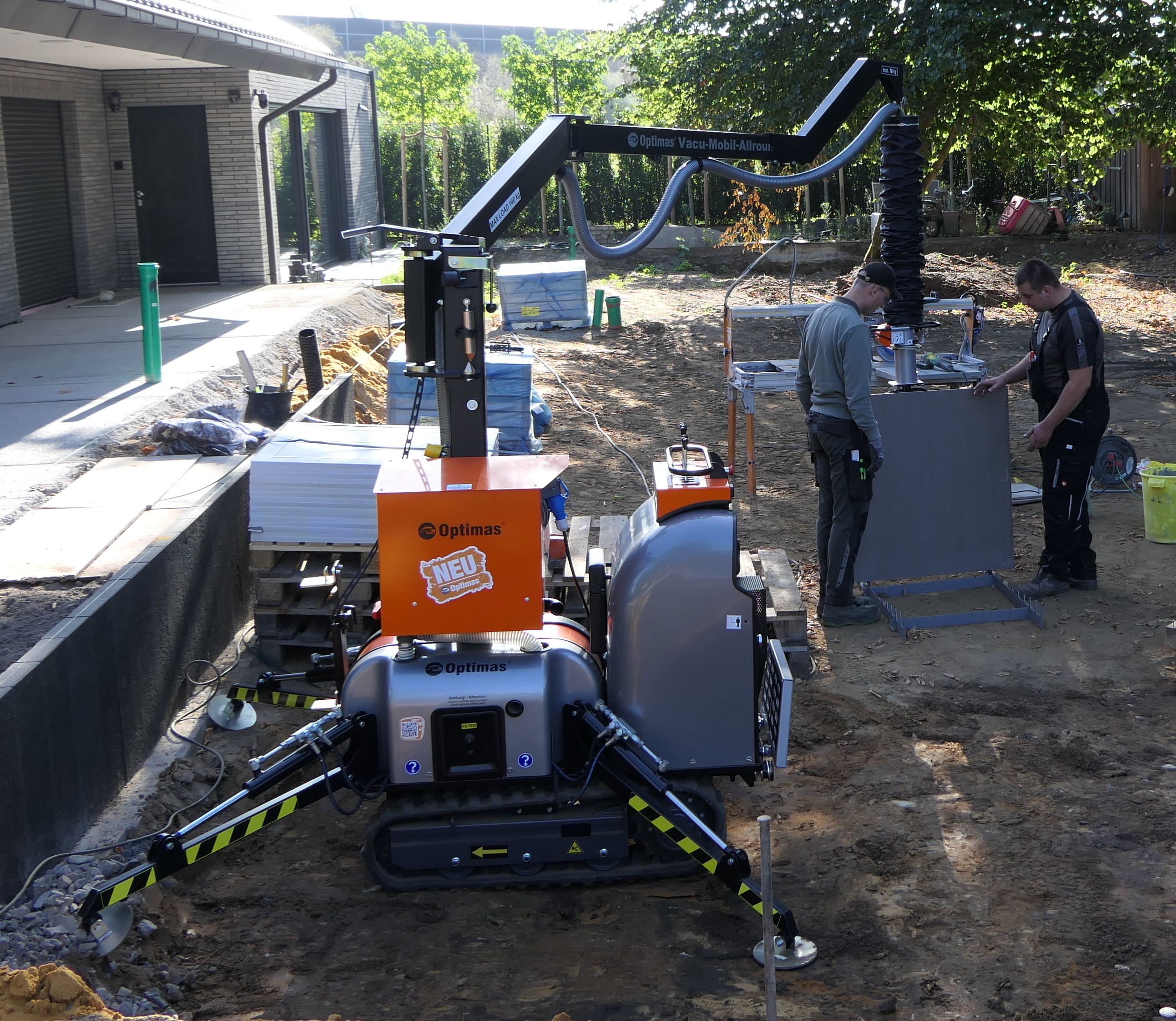 Zwei Bauarbeiter montieren eine große graue Platte mit einem Optimas-Vakuumhebegerät für den Einbau und demonstrieren dabei sicheres und effizientes Handling – Optimas.
