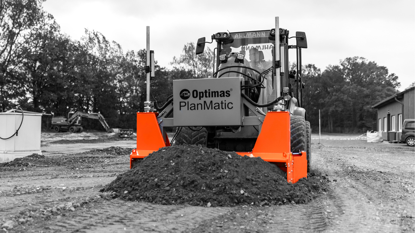 A construction vehicle equipped with an orange attachment moves dirt on a job site – Optimas.