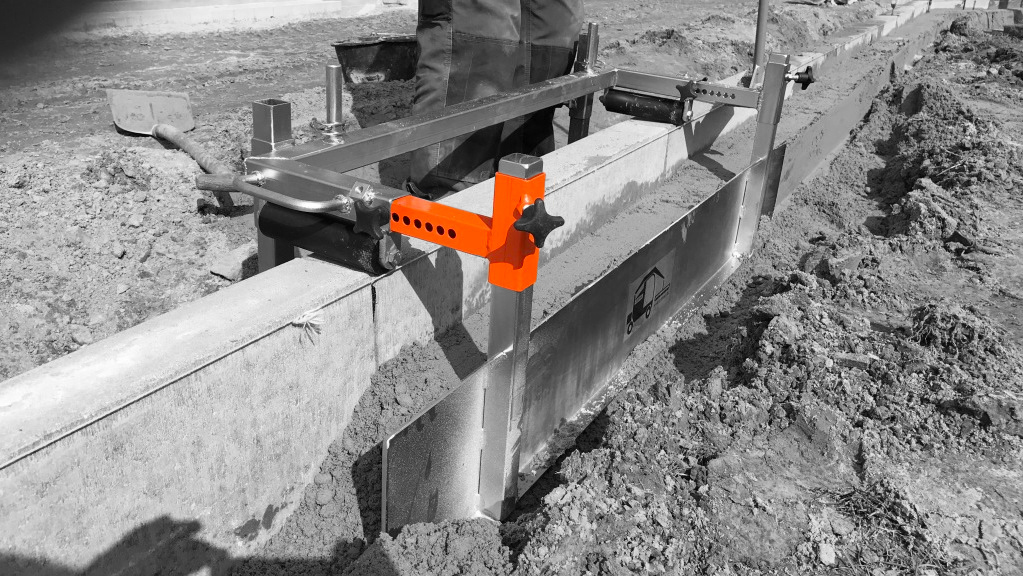 A construction worker uses a tool to level concrete along a foundation, showcasing precision in building – Optimas.