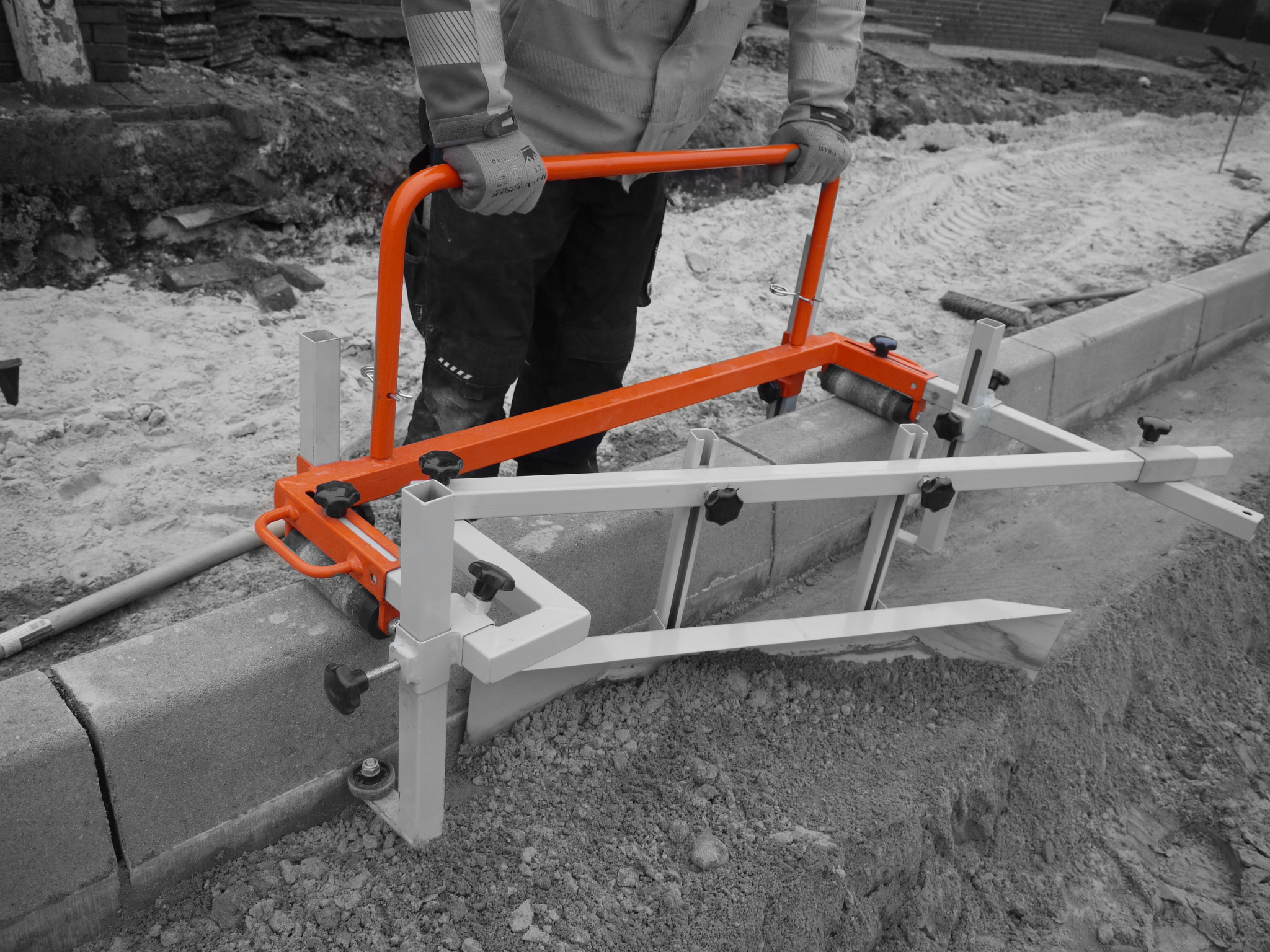 A worker using a concrete leveling tool on a construction site with a focus on the orange handle – Optimas.