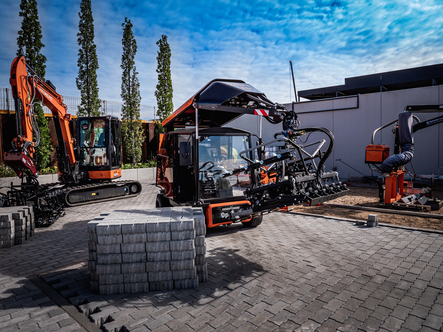 Construction site featuring various machinery, including excavators and block stacking equipment – Optimas.