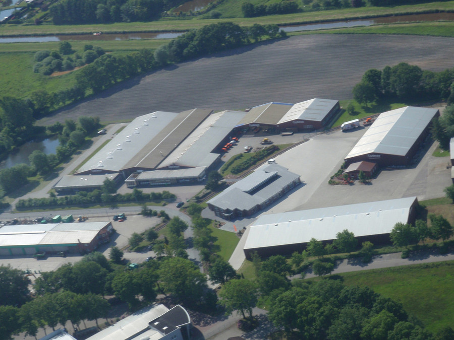 Aerial view of a large agricultural facility with multiple buildings and surrounding greenery – Optimas.