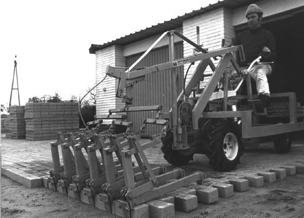 A worker operates a specialized machine laying bricks on a construction site, showcasing efficient masonry work – Optimas.