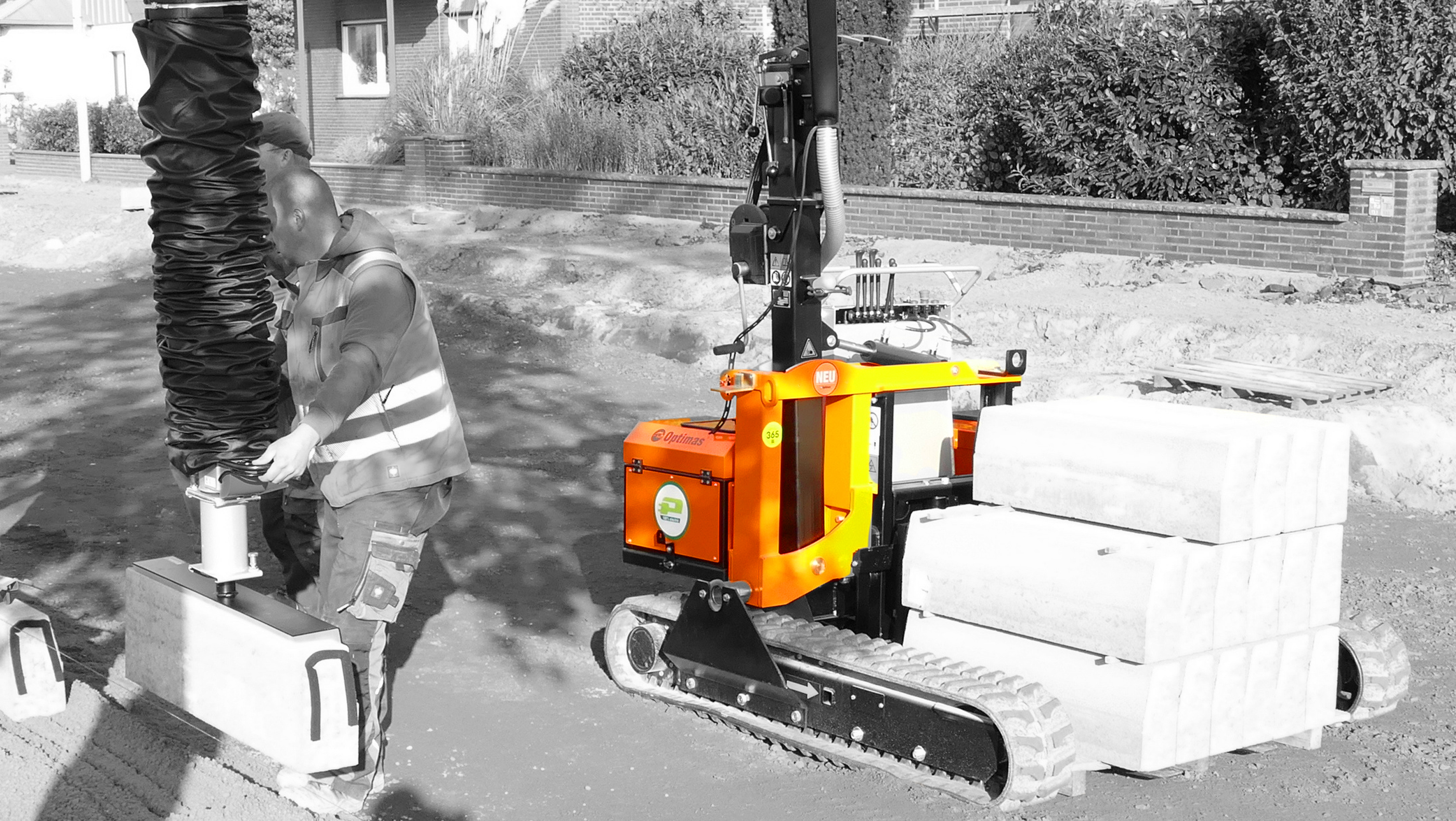 A construction worker operates a compact machine lifting concrete blocks on a construction site – Optimas.
