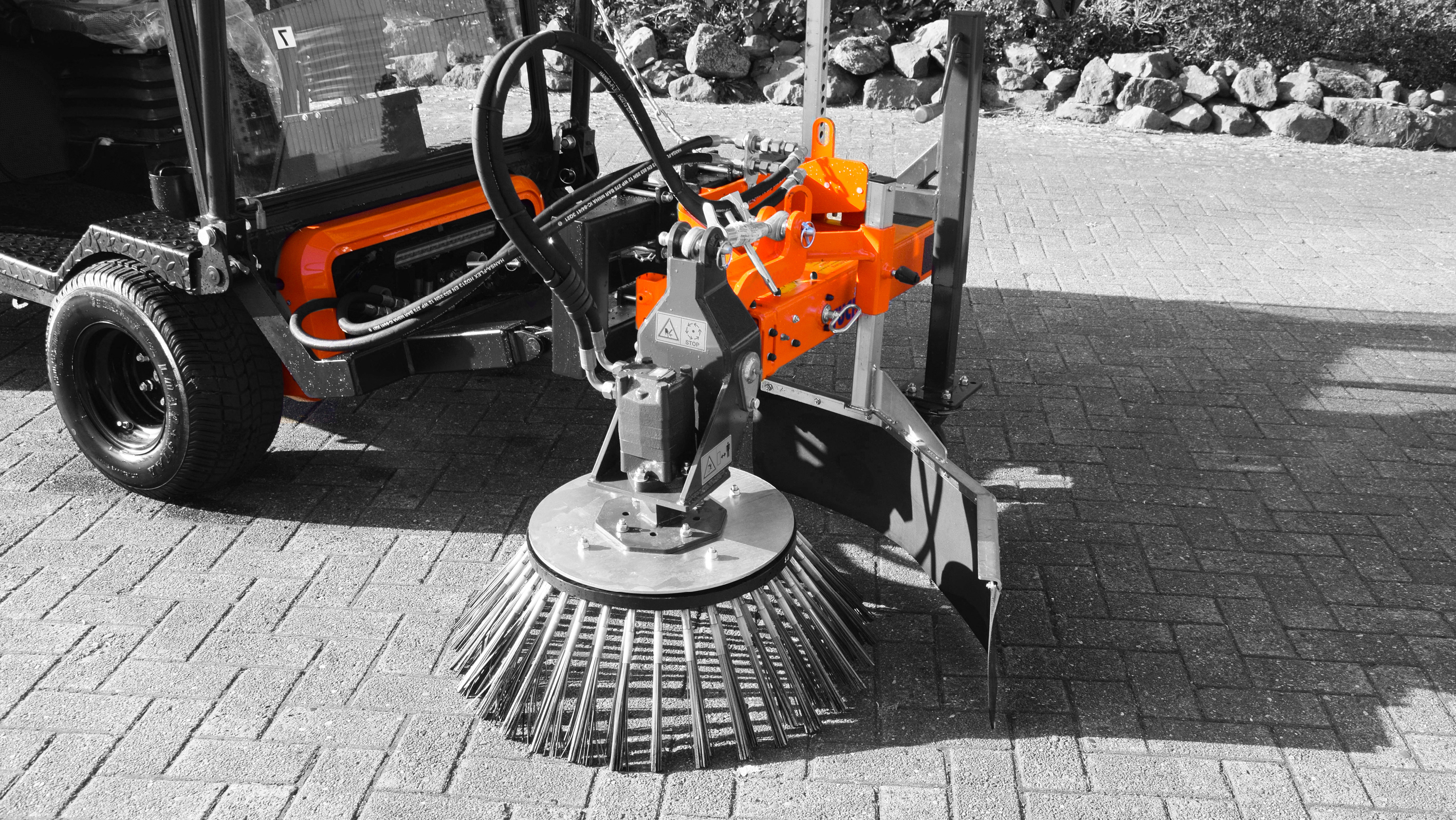A close-up of a specialized cleaning attachment on a vehicle, featuring a rotating brush and metal components – Optimas.