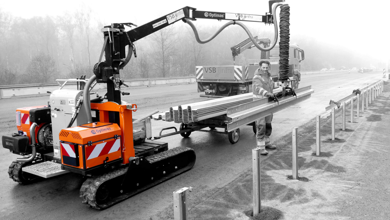 Optimas curb laying machine assisting a construction worker with guardrail installation on the roadside, improving safety efficiently– Optimas.